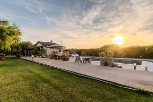 a house with a patio and a lawn with the sunset at Villa Lavinia in Alghero