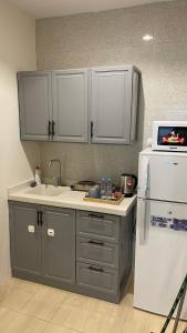 a kitchen with gray cabinets and a white refrigerator at غرفتين وصالة بدخول ذكي in Al Kharj
