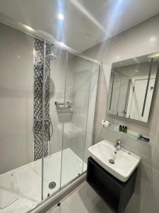 a white bathroom with a shower and a sink at K Hotel Kensington in London +27 photos