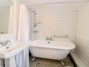 a white bathroom with a tub and a sink at Vintner's Cottage in Norwich +20 photos