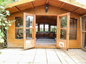 an open door of a wooden shed with a bench inside at Vintner's Cottage in Norwich