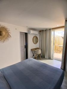a bedroom with a bed and a view of a patio at Hôtel Quai d'Azur in Le Grau-du-Roi