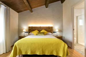 a bedroom with a large bed with a yellow blanket at El Mas de Mateus in Sagás +16 photos