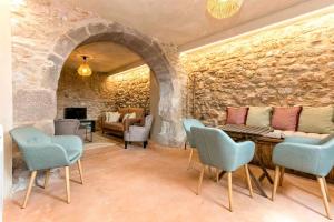 a room with a stone wall with a table and chairs at El Mas de Mateus in Sagás