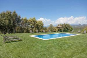 a swimming pool in the middle of a lawn with chairs at El Mas de Mateus in Sagás