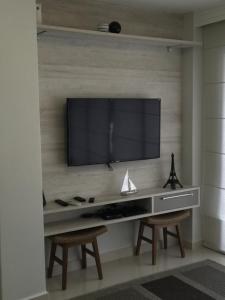 un salon avec une télévision sur un mur et deux chaises dans l'établissement Apartamento Spiaggia Del Sole, à Guarujá