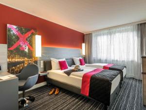 a hotel room with a large bed and a desk at Mercure Hotel Düsseldorf Zentrum in Düsseldorf +55 photos