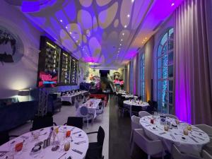 a dining room with white tables and purple lighting at Cures Marines Hotel Thalasso & Spa Trouville - MGallery Collection in Trouville-sur-Mer +192 photos
