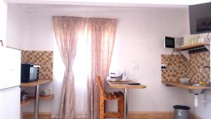 a kitchen with a window and a desk with a chair at Shalom Self Catering in Lüderitz