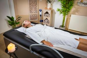 a woman laying in a bed in a room at Hotel Allmer in Bad Gleichenberg
