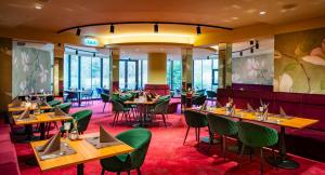 a restaurant with wooden tables and green chairs at Hotel Allmer in Bad Gleichenberg