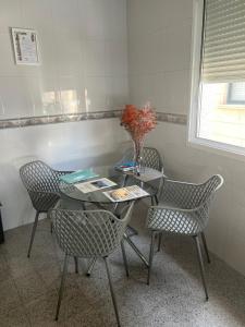 a table with chairs and a vase with flowers on it at LolaREDONDELA in Redondela