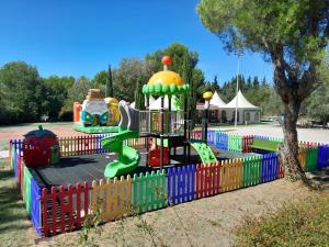 a playground in a park with a colorful fence at Camping Fontisson in Châteauneuf-de-Gadagne