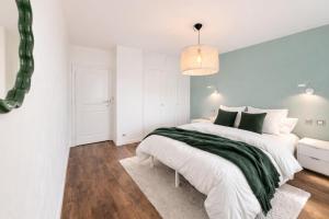 a white bedroom with a large bed with a green blanket at M046 T3 cosy 2 chambres et balcon in Ambilly +4 photos