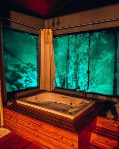 a bath tub in a room with two windows at Refúgio do Vale Estalagem in Annitapolis +50 photos
