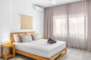 a white bedroom with a large bed and a window at Golden Bloom - High-End Duplex w Private Pool in Rivière Noire