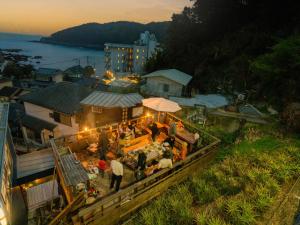a group of people standing around a restaurant with lights at Guesthouse All you need - All rooms have an ocean view! in Shimoda