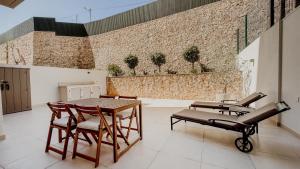 a patio with a table and chairs and a brick wall at Alta de Faro in Faro