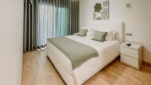 a bedroom with a large white bed and a window at Alta de Faro in Faro