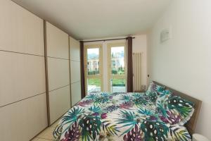 a bedroom with a bed with a colorful comforter and a window at Casa Vacanza Ninfea in Paratico