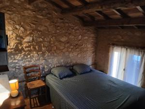 a bedroom with a bed and a stone wall at Les Bergeries d Orkan in Châteauneuf-du-Rhône
