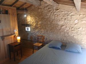 a bedroom with a bed and a stone wall at Les Bergeries d Orkan in Châteauneuf-du-Rhône