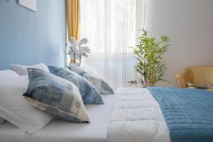 a bed with blue and white pillows and a window at Actinia Accommodation in Alghero