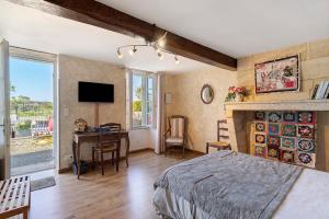 a bedroom with a bed and a desk and a tv at Chambre d'Hotes La Roseraie in Saint-Émilion