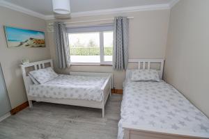 two beds in a small bedroom with a window at Castle View in Oughterard