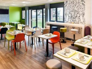 a restaurant with tables and chairs with cups on them at ibis budget Goussainville Charles de Gaulle in Goussainville