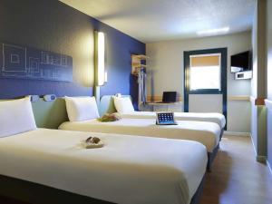 a row of three beds in a hotel room at ibis budget Albi Terssac in Terssac