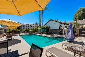 a swimming pool with chairs and umbrellas at Sonesta ES Suites Phoenix Goodyear in Goodyear