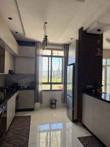 a kitchen with white cabinets and a large window at Comfort House in Azib Aïn el Alak +21 photos