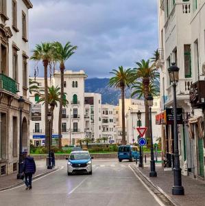 a city with palm trees and cars on a street at Comfort House in Azib Aïn el Alak