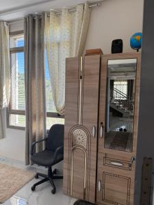a room with a cabinet and a chair and a window at Comfort House in Azib Aïn el Alak