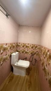 a bathroom with a toilet and flowers on the wall at Utkarsh Palace And Restaurant in Ayodhya Ghā