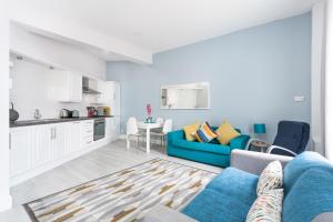 a living room with a blue couch and a kitchen at Walled City Apartments in Derry Londonderry