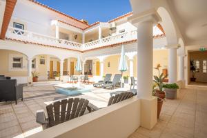 a house with a patio with chairs and umbrellas at Rosa dos Ventos in Zambujeira do Mar