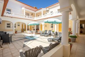 a patio with chairs and tables and umbrellas at Rosa dos Ventos in Zambujeira do Mar