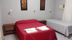 a bedroom with two beds with red sheets and white towels at Posada el circulo in Chamical