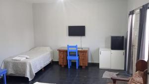 a bedroom with a bed and a desk with a blue chair at Posada el circulo in Chamical