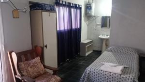 a bedroom with a bed and a chair and a sink at Posada el circulo in Chamical