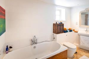 a white bathroom with a tub and a toilet at Finest Retreats - Mill Barn By The Stream in West Lydford +18 photos