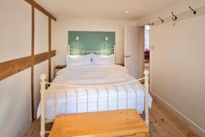 a bedroom with a white bed and a wooden bench at Finest Retreats - Mill Barn By The Stream in West Lydford