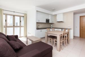 ein Wohnzimmer mit einem Sofa und einem Tisch sowie eine Küche in der Unterkunft TAO Morro Jable in Morro del Jable