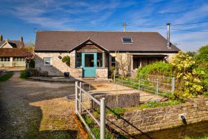 a house with a blue door and a fence at Finest Retreats - Mill Barn By The Stream in West Lydford