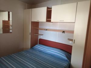 a small bedroom with a bed and white cabinets at Camping Paradiso in Viareggio +54 photos