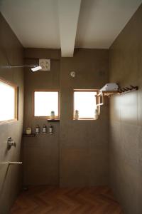 a bathroom with a shower with a glass door at The Windbloom - Himalayan Farm Stay in Mukteshwar