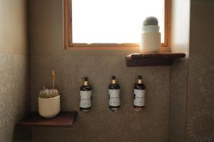 three bottles of wine on a wall with a window at The Windbloom - Himalayan Farm Stay in Mukteshwar