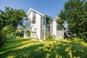 a white house with glass windows on a lawn at Song Đan Villa in Sóc Sơn